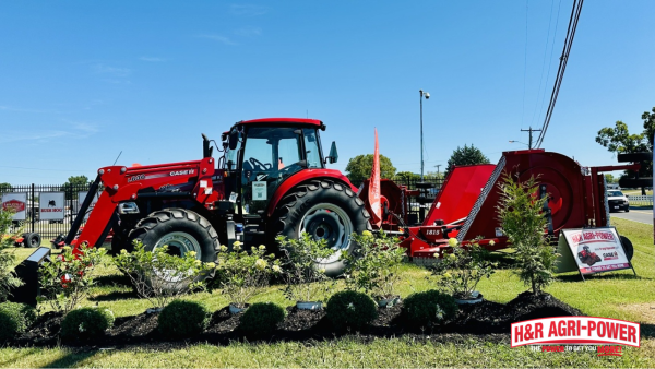 Case IH tractor connected to a red Bush Hog rotary cutter at a dealership display.
