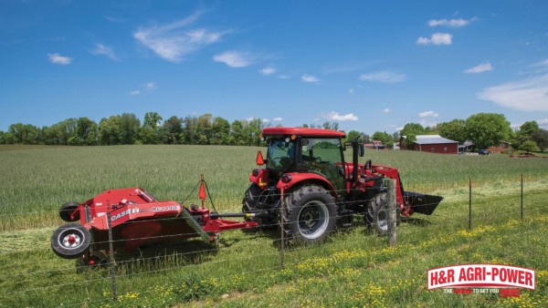 Case IH tractor pulling a rotary cutter through pasture grass near a fence line