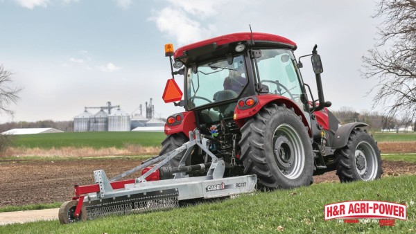 Case IH tractor with rotary cutter mowing roadside vegetation near farm fields