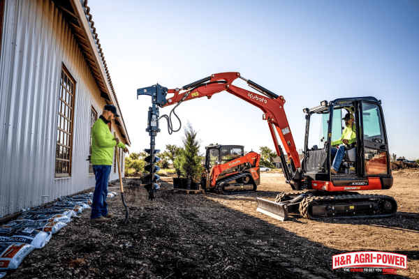 Kubota compact excavator with auger attachment drilling into soil for efficient land improvement and construction tasks
