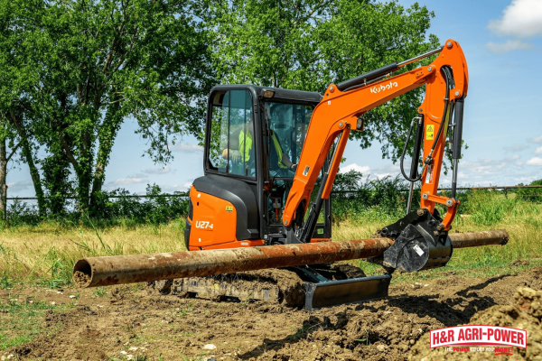 Kubota compact excavator lifting a pipe with precision, highlighting power and control for detailed construction work