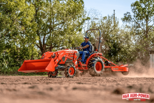 Kubota tractor with front loader and backhoe attachment preparing soil for fieldwork and land management