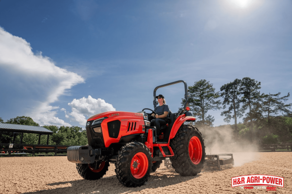 Operator driving Kubota tractor in an open field, highlighting ergonomic controls and operator comfort features