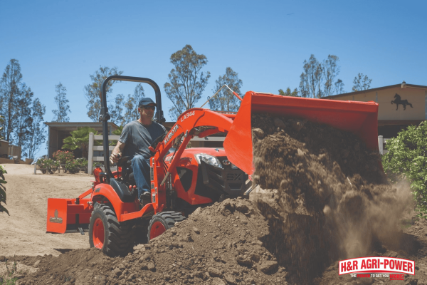 Kubota tractor using front loader attachment to move dirt safely during operationv