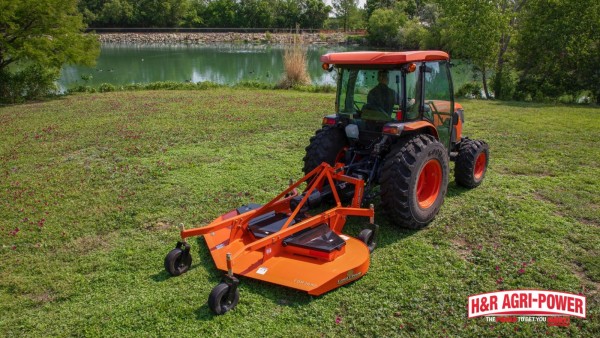 Kubota tractor with front loader and rotary cutter maintaining brush near a food plot fence line