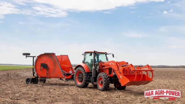 Kubota tractor with front loader and rotary cutter attachment working in an open field