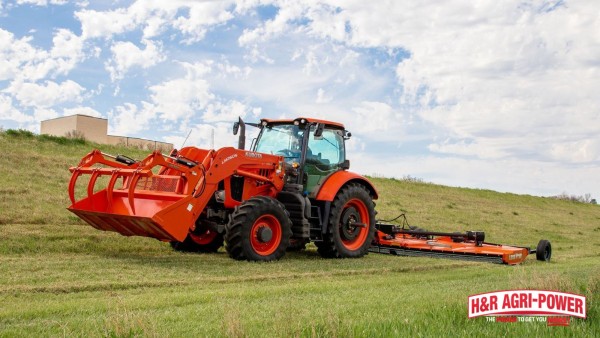 Kubota tractor with front loader pulling a wide Land Pride brush hog across a pasture
