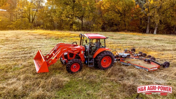 Kubota tractor using a wide Land Pride bush hog to cut a large open field