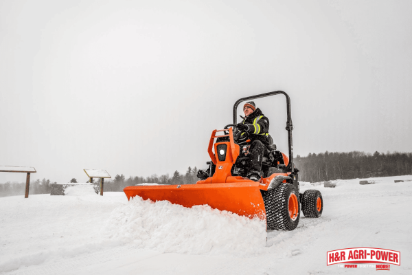 Kubota equipment clearing snow, representing the choice between DIY maintenance and professional winterization services