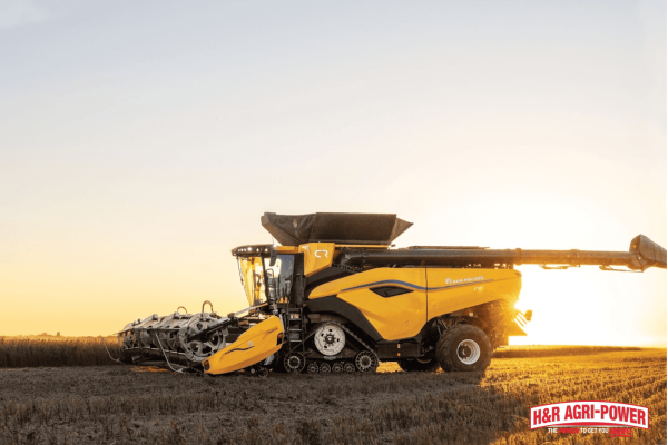 New Holland combine at sunset in a harvested field, representing proper winterization and storage after seasonal use