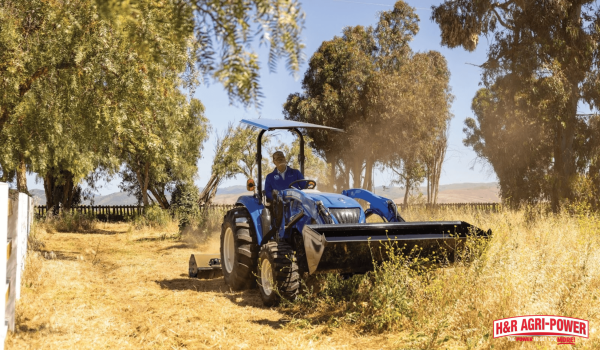 New Holland compact tractor mowing field for small acreage property maintenance