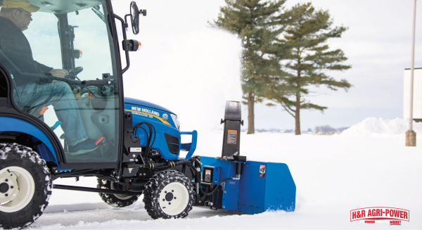 New Holland compact tractor operating a front-mounted snow blower in winter conditions to demonstrate proper attachment matching for efficient performance