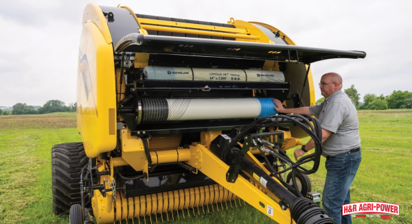 Technician inspecting hydraulic components inside New Holland round baler during repair service