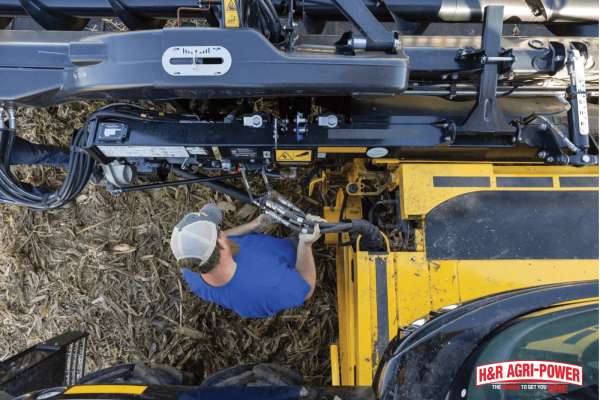 Technician performing maintenance on New Holland equipment, showing how to track and manage service schedules effectively