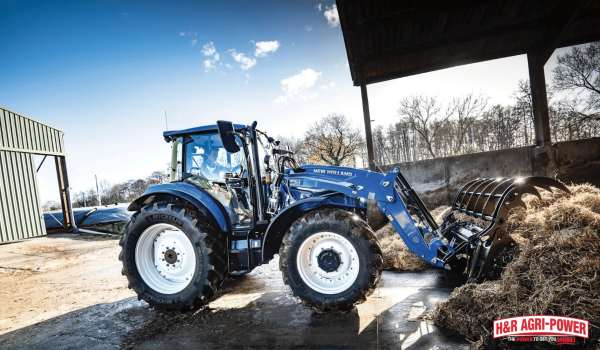 New Holland tractor with front loader handling hay on farm highlighting equipment support and service reliability