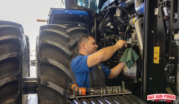 Technician servicing New Holland tractor during maintenance to evaluate long-term equipment ownership costs