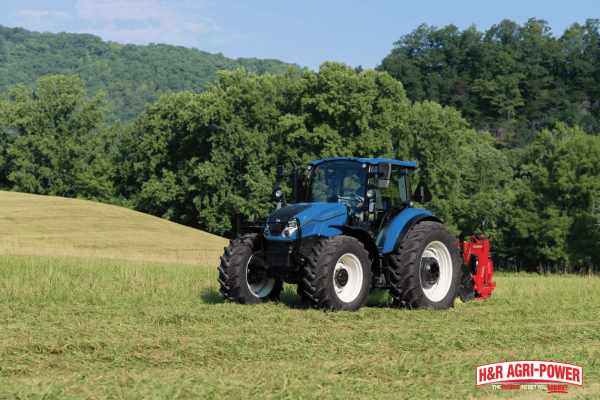 New Holland tractor working in a field, illustrating proper service intervals for engine, transmission, and hydraulic systems