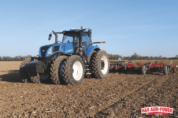 New Holland tractor pulling tillage equipment across farmland, showing proper operation techniques that extend machinery lifespan