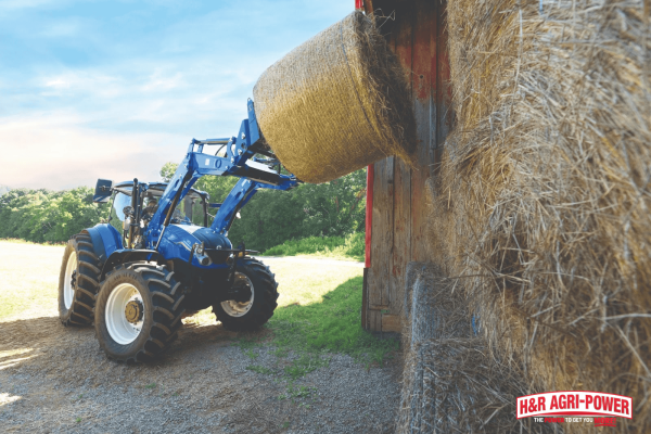 New Holland tractor lifting a hay bale, highlighting tire condition and undercarriage maintenance for reliable operation