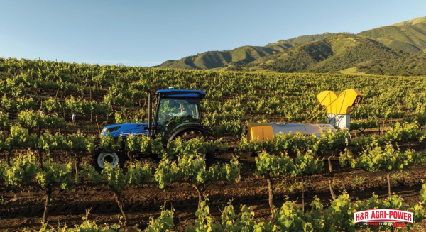 New Holland vineyard tractor operating on hillside terrain with rear implement attachment for safe vineyard management