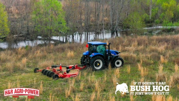 Tractor using a Bush Hog rotary cutter to clear tall grass near a wooded wildlife area