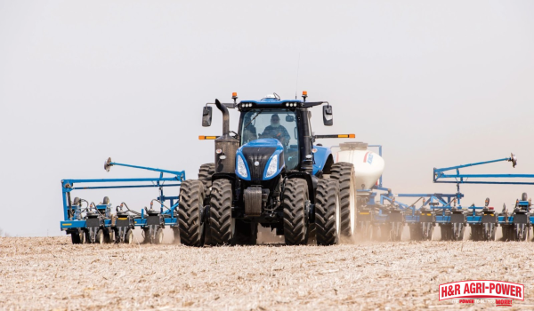 New Holland tractor operating with wide tillage implement in field demonstrating safe spring planting operations
