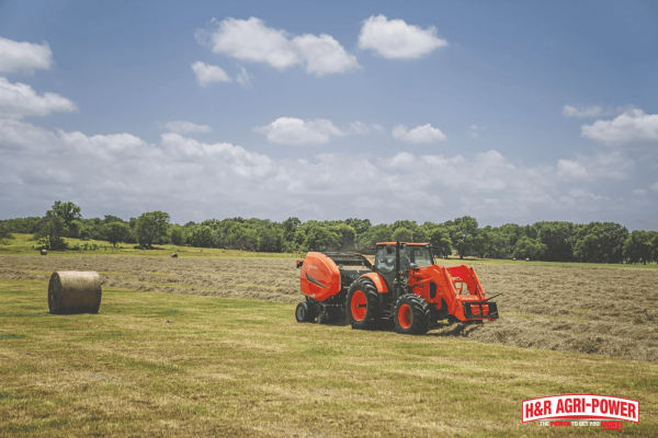 Kubota tractor and round baler operating in a Tennessee hay field, showcasing durable equipment for hay production and farm operations.