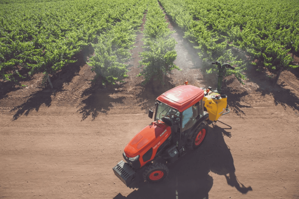 Autonomous Kubota M5N tractor performing precision spraying in vineyard rows to reduce labor needs, improve efficiency, and enhance crop safety for specialty crop growers.