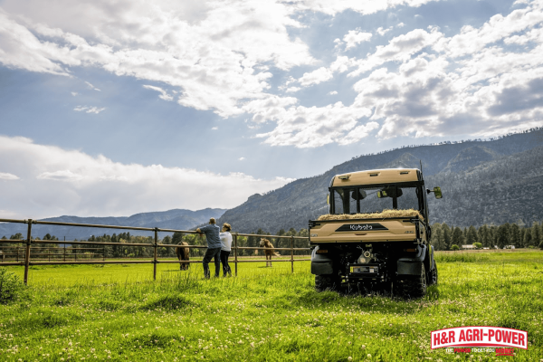 Kubota RTV utility vehicle parked in a pasture near livestock fencing, demonstrating durability and versatility for everyday farm operations.