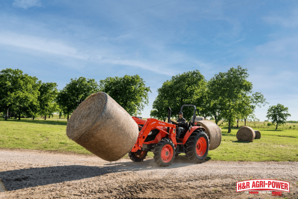 Kubota tractor using a front loader to transport a large round hay bale on a Mississippi farm, showcasing real-world performance and everyday farm productivity.