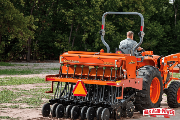 Kubota tractor using a seed drill attachment for planting in a prepared field