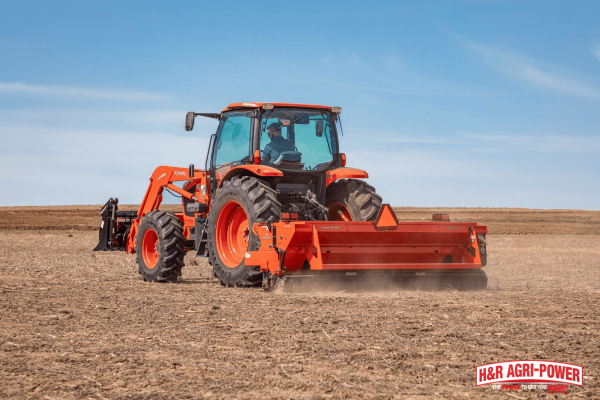 Kubota tractor operating a tillage implement in a field during spring soil preparation