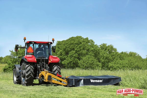 Tractor and baler operating in a Tennessee hay field, showcasing efficient hay production supported by professional equipment service.